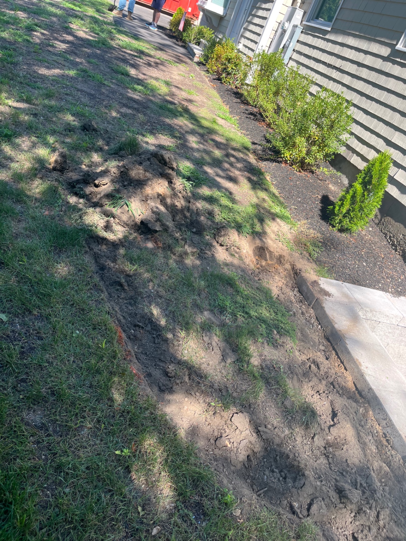 Excavated trench alongside a new concrete walkway